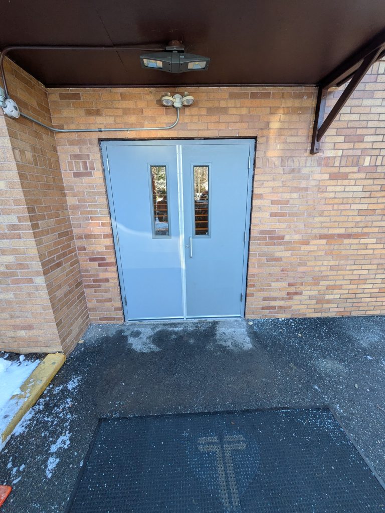 Light blue steel double doors with vision lites at a commercial entrance