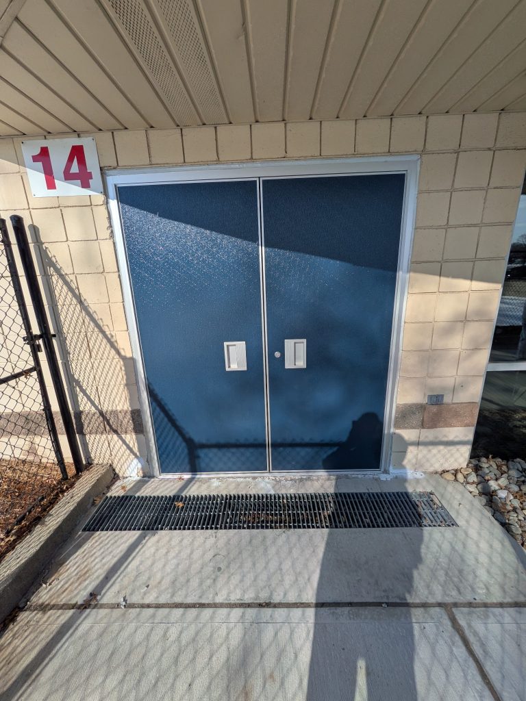 Pair of blue steel commercial doors with louvers and panic hardware